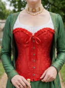 zbliżenie na czerwony gorset na kobiecie, która nosi także zieloną narzutę i perłowy naszyjnik