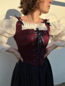 kobieta w gorsecie sznurowanym na białej koszuli trzymająca się pod boki