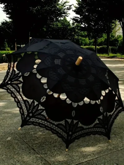 czarna parasolka koronkowa leżąca na trawie w parku