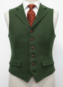 Zbliżenie na fakturę zielonej tkaniny tweedowej w wzór jodełki, widoczne brązowe guziki i kieszeń.