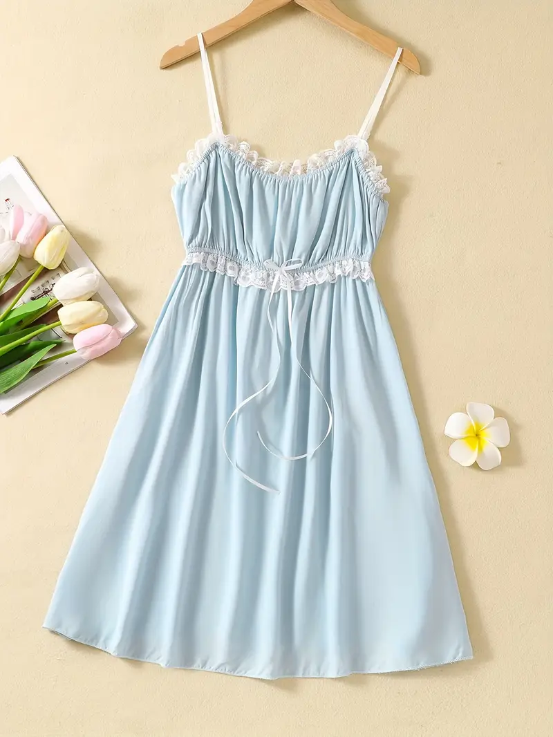 niebieska koszula nocna na ramiączkach na beżowym tle obok bukietu kwiatów