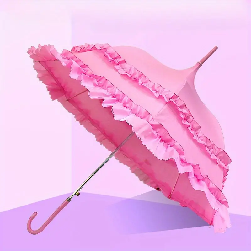 parasolka koronkowa vintage położona przy różowej ścianie