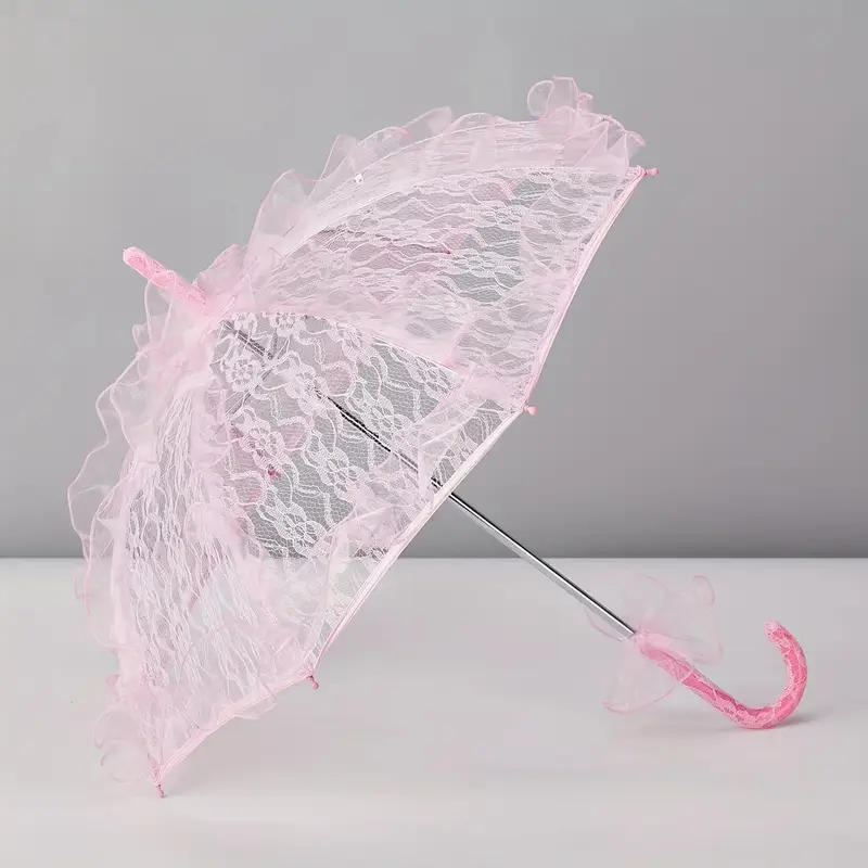 różowa parasolka koronkowa obrócona bokiem na szarym tle