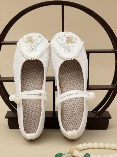 białe buty vintage damskie do tańca oparte na drewnianej ramie na beżowym tle