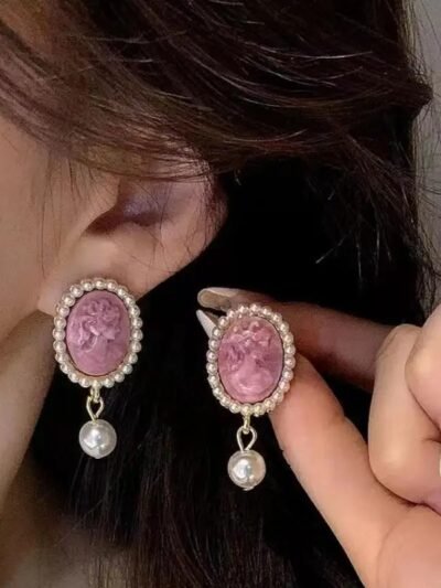 kobieta z brązowymi włosami nosząca różowe kolczyki vintage z perłą