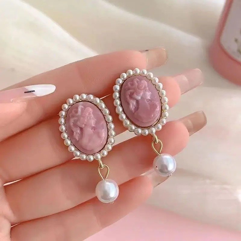 francuskie kolczyki vintage w dłoni kobiety