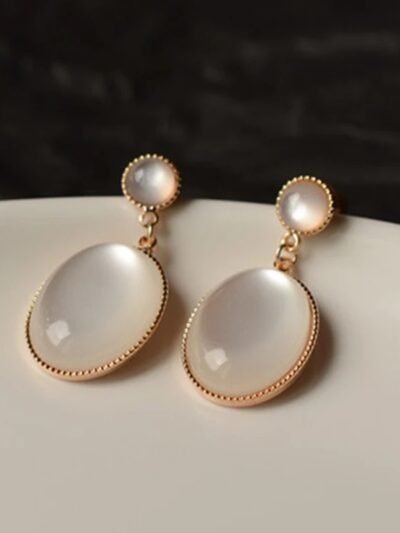 kolczyki vintage z przezroczysto-białym kamieniem obrócone bokiem na białym talerzu