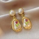 złote kolczyki vintage z różą na beżowym jedwabistym materiale