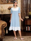 kobieta z czarnymi włosami ozdobionymi srebrną tiarą ubrana w jasnoniebieską koszulę do spania w starodawnym salonie