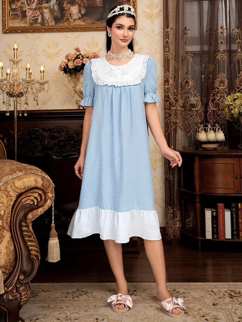 kobieta z czarnymi włosami ozdobionymi srebrną tiarą ubrana w jasnoniebieską koszulę do spania w starodawnym salonie