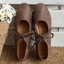 brązowe starodawne sznurowane buty vintage damskie oparte o białe deski