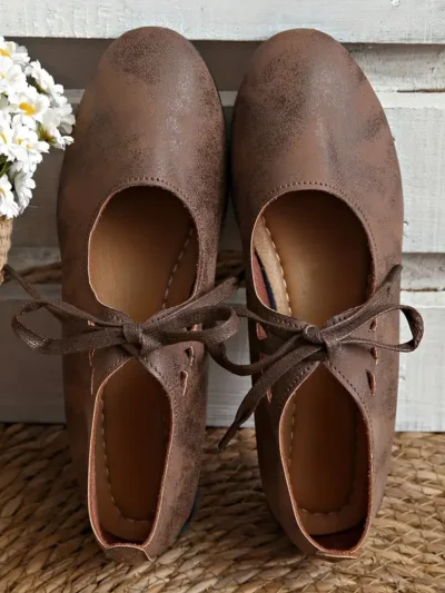 brązowe starodawne sznurowane buty vintage damskie oparte o białe deski