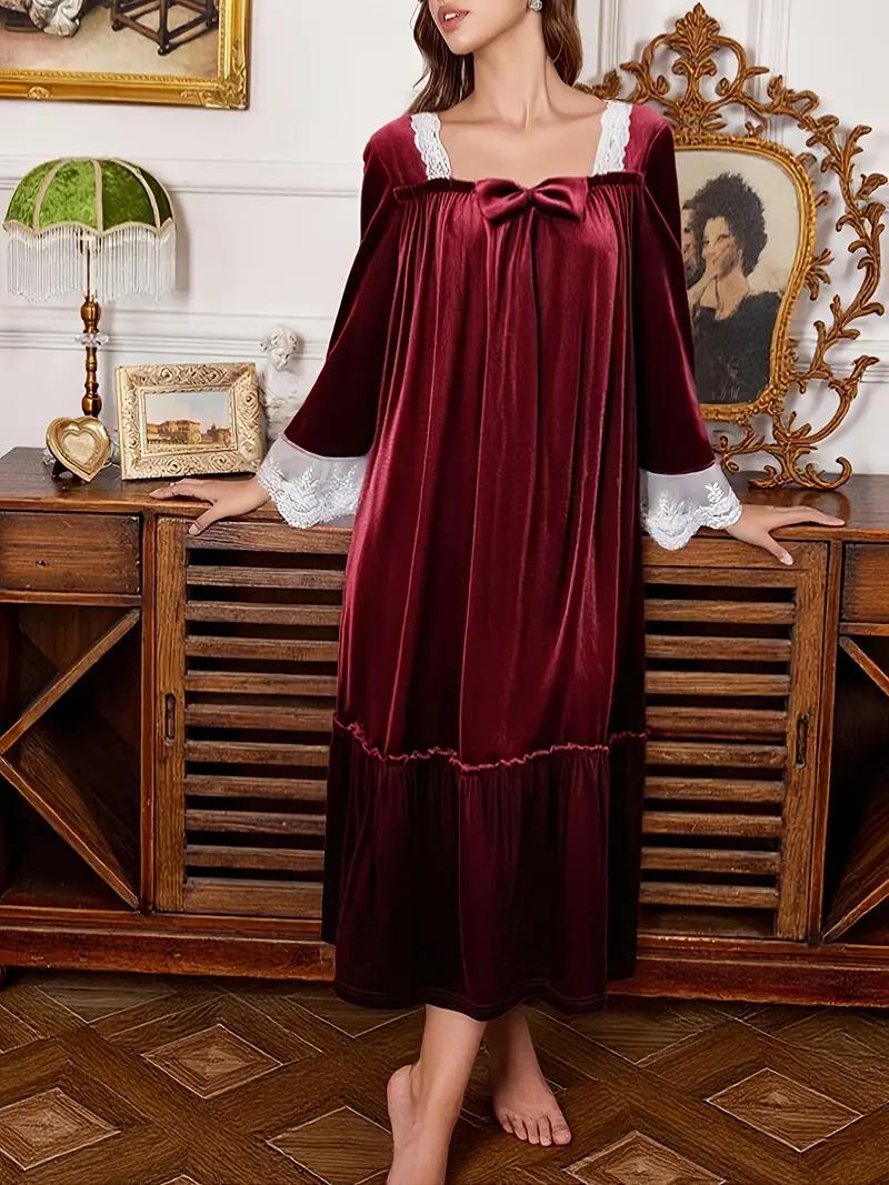 kobieta ubrana w bordową welurową koszulę nocną, opierająca się o drewnianą szafkę nocną