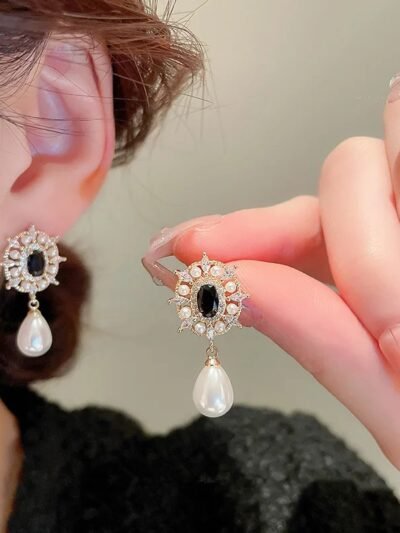 kobieta trzymająca jeden z wiszących kolczyków vintage i trzymająca drugi