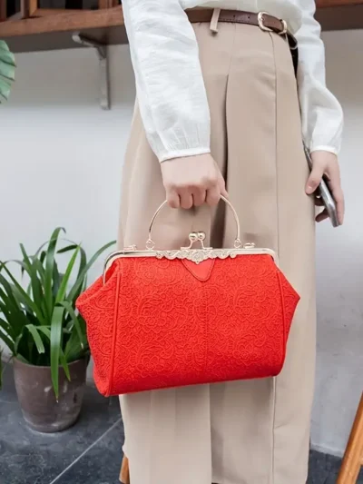 kobeta w eleganckich beżowych spodniach trzymająca czerwoną torebkę vintage