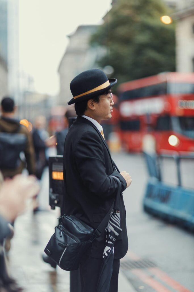 mężczyzna noszący czarny elegancki płaszcz oraz skórzaną torbę pokazując, do czego nosić kapelusz męski