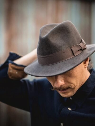 mężczyzna noszący szary kapelusz fedora męski oraz granatowy frak