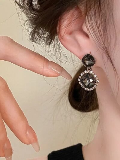 kobieta nosząca wiszące kolczyki vintage z cyrkoniami