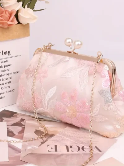 różowa zdobiona kopertówka vintage postawiona na lśniącej powierzchni obok gazet