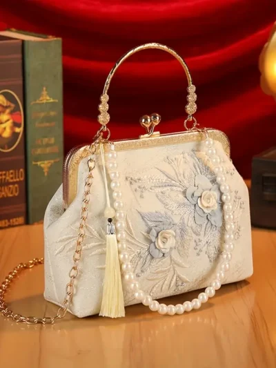 kwiatowa torebka vintage z niebieską haftowaną różą na drewnianym biurku