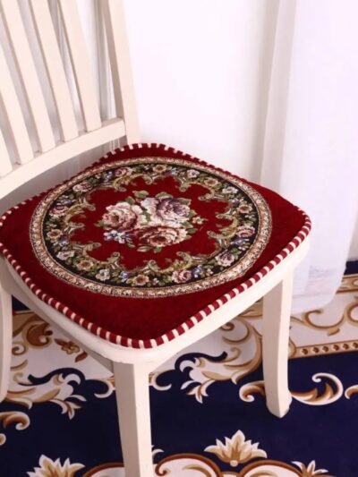 czerwona poduszka na krzesło vintage ze wzorem w róże na białym krześle