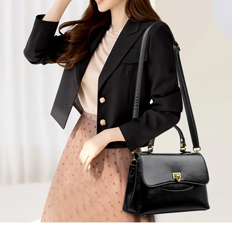kobieta nosząca na ramieniu czarną torebkę vintage skórzaną oraz czarną marynarkę i beżową spódnicę