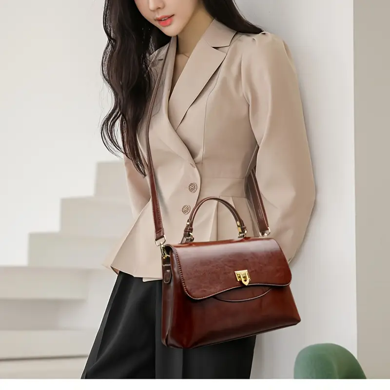 kobieta z czarnymi włosami nosząca brązową troebkę vintage skórzaną, beżową marynarkę oraz czarne spodnie