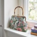 torebka vintage z kwiatowym wzorem położona na białym parapecie obok książek