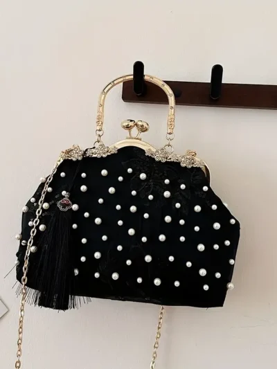 czarna torebka vintage z perłami zawieszona na ciemnym drewnianym wieszaku
