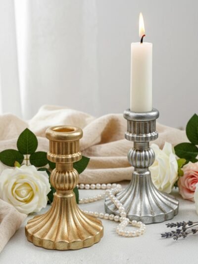 złoty oraz srebrny świecznik vinteg ze wzorem muszli położony na stole obok białych róż