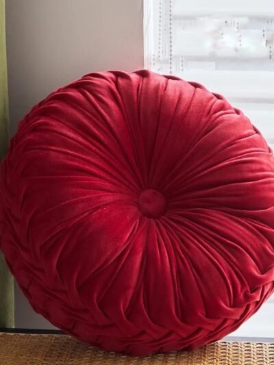 okrągła czerwona dekoracyjna poduszka vintage oparta o parapet przy oknie