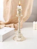 dekoracyjny świecznik vintage z białą świecą położony na białym stole