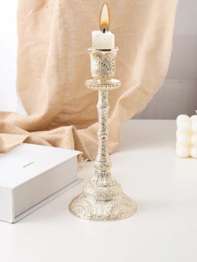 dekoracyjny świecznik vintage z białą świecą położony na białym stole