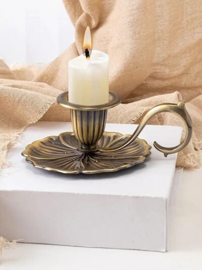 Starodawny stojak na świeczkę z białą świecą w środku położony na białym podwyższeniu