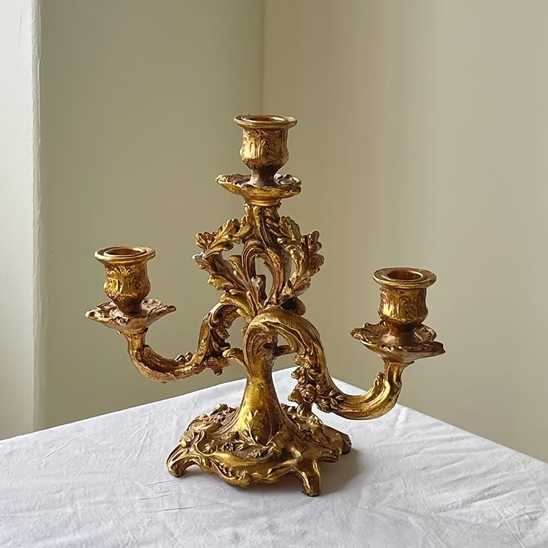 złoty trójgłowy barokowy świecznik położony na białym obrusie