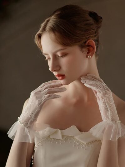 kobieta z brązowymi włosami upiętymi w kok nosząca biale koronkowe rękawiczki