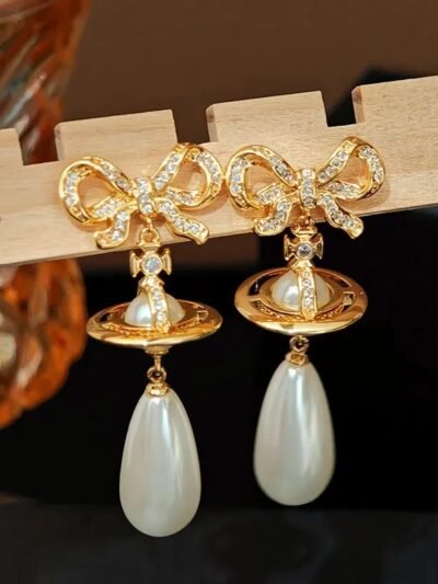 złote błyszczące kolczyki vintage z perłą położone na desce