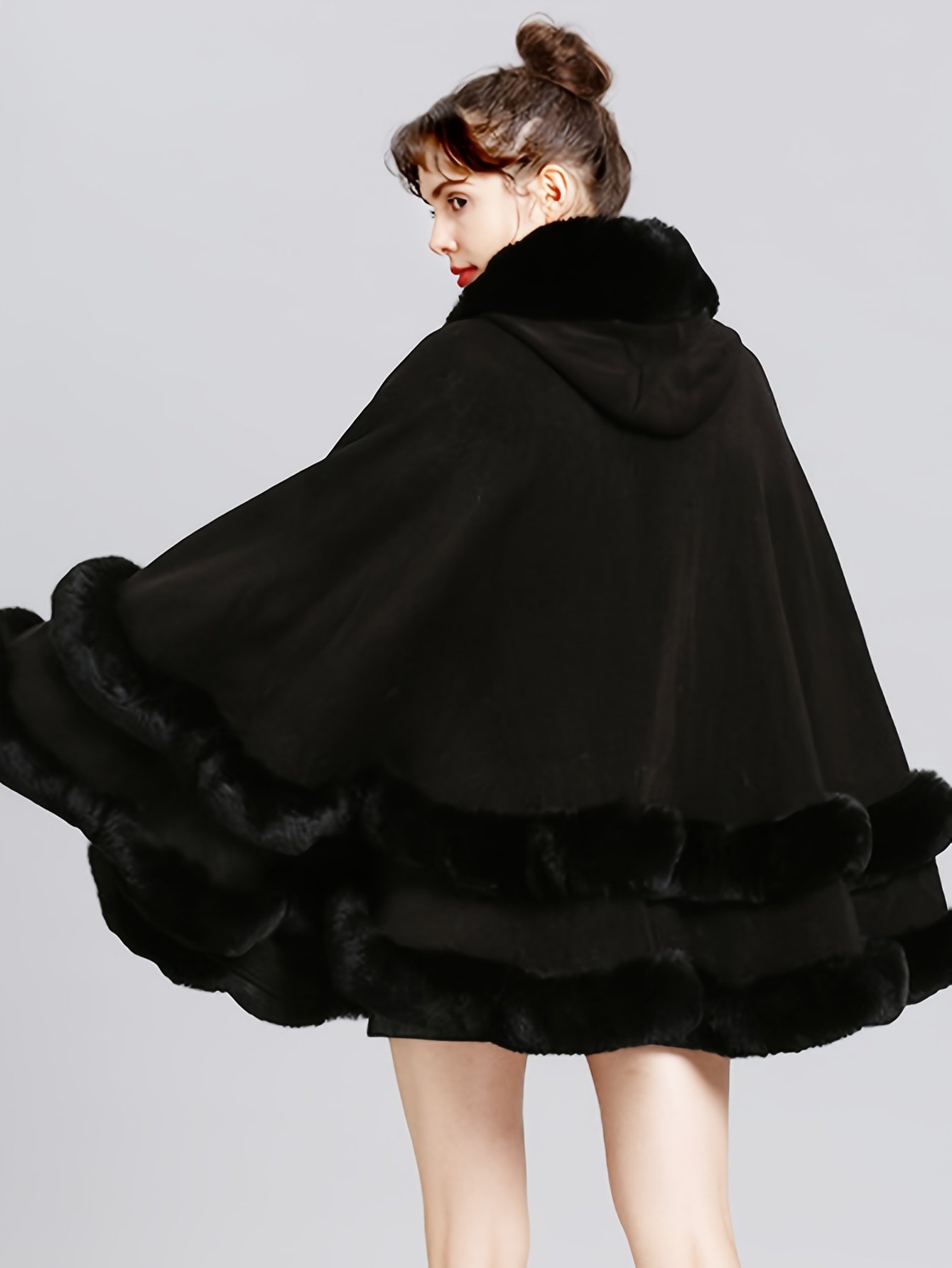 kobieta nosząca czarną dwuwarstwową pelerynę damską obrócona tyłem