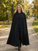 kobieta z blond włosami ubrana w czarną pelerynę damską w parku