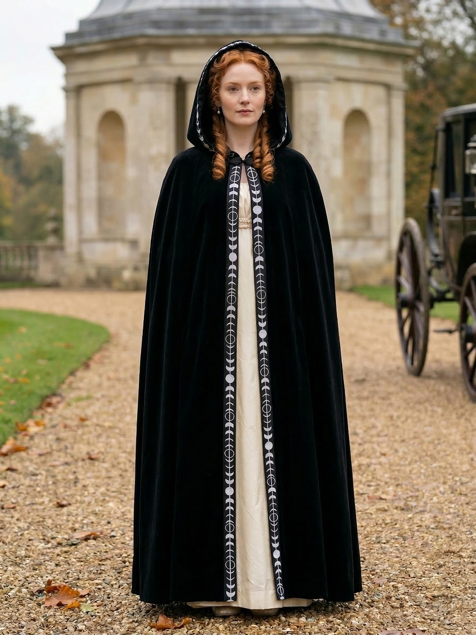 kobieta z rudymi włosami wpatrzona w dal ubrana w czarną dawną damską pelerynę na ścieżce