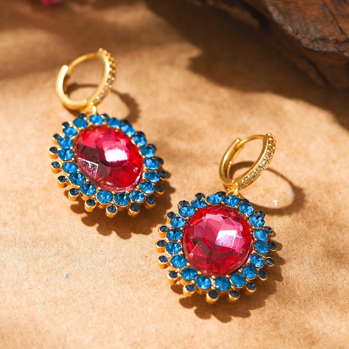 różowo-niebieskie duże kolczyki vintage obrócone bokiem na beżowym tle