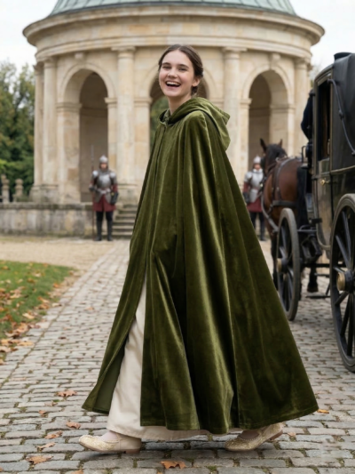 kobieta idąca kamienną drogą w zielonym płaszczu pelerynie i białych butach