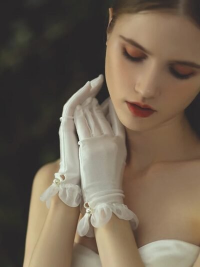 kobieta nosząca białe rękawiczki z satyny oraz przykładająca dłonie do twarzy