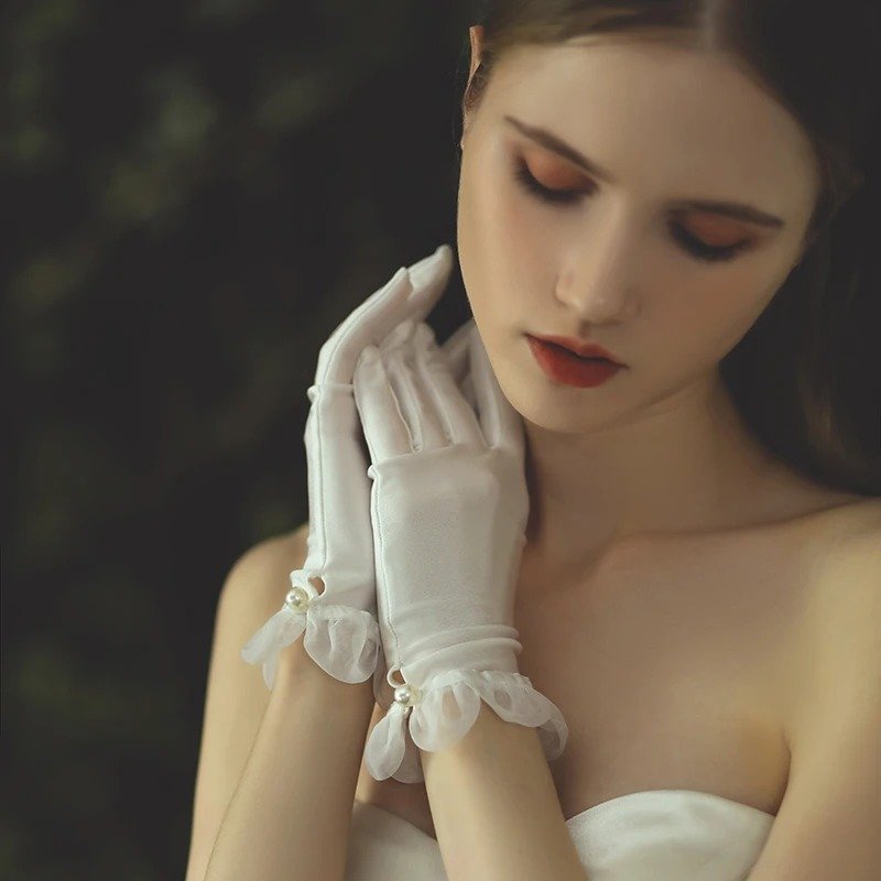 kobieta nosząca białe rękawiczki z satyny oraz przykładająca dłonie do twarzy