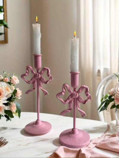 różowy świecznik z białą świeczką położony na eleganckim stole obok róż