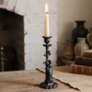 stary świecznik ze zdobieniami z białą świeczką w środku położony na stole