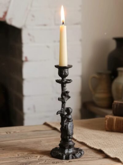 stary świecznik ze zdobieniami z białą świeczką w środku położony na stole