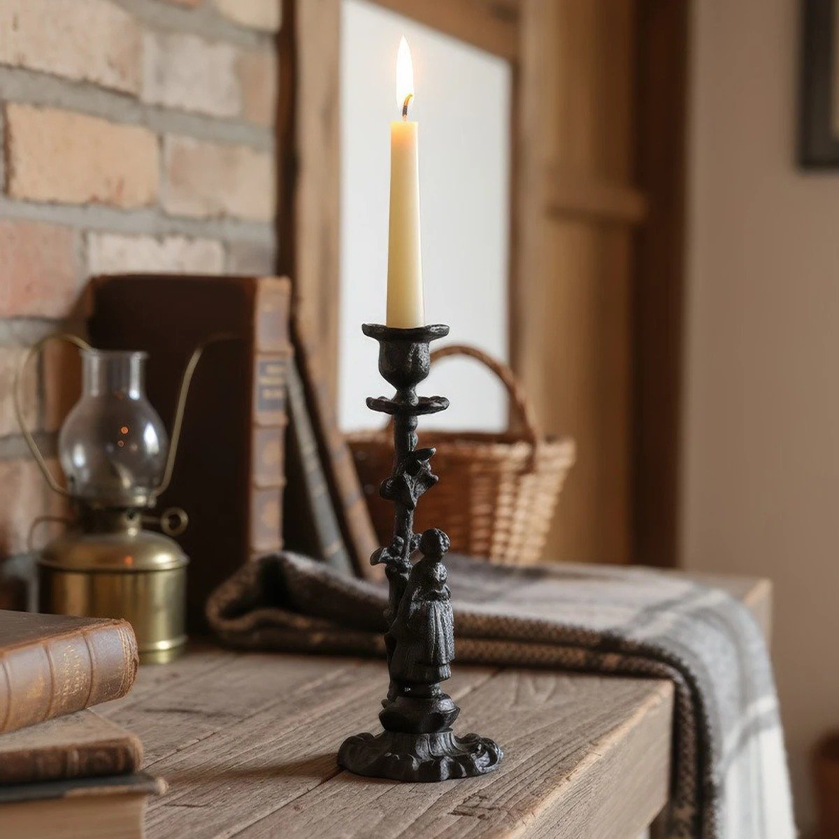 czarny stary świecznik z palącą się świeczką położony obok koszyka