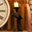 świecznik gotycki z palącą się świeczką połozony obok wielkiego zegara