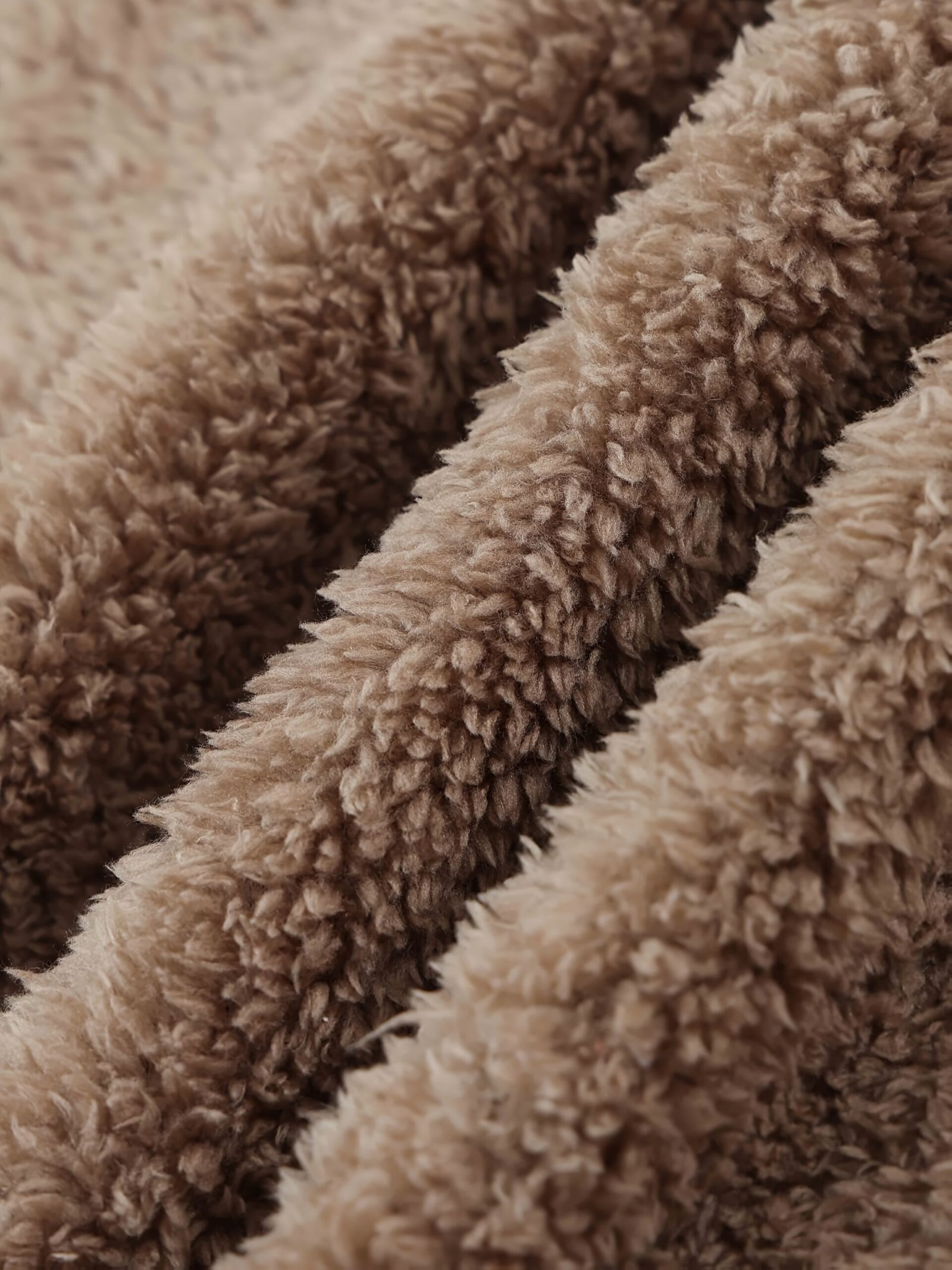 zbliżenie na puchowy materiał beżowej ciepłej peleryny damskiej